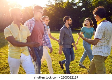 Group of cheerful friends hanging out in a beautiful park. Six happy young diverse multiethnic people enjoying good summer weather, walking on a green lawn, talking and having fun together - Powered by Shutterstock