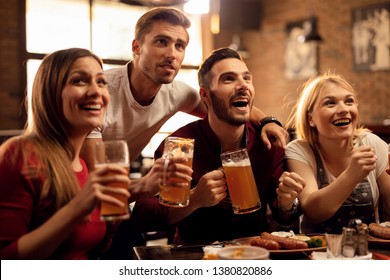 Group Of Cheerful Friends Having Fun While Watching Sports Game On TV And Drinking Beer In A Bar. 