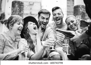 Group of cheerful friends having a party in the city throwing confetti and drinking champagne - Beautiful young people laughing having fun on the street drinking  prosecco celebrating a birthday