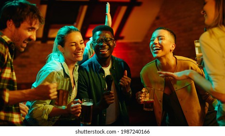 Group of cheerful friends singing and having fun while gathering on a night party at the bar. - Powered by Shutterstock