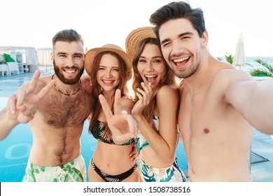 Group of cheerful friends standing together at the poolside, taking a selfie with mobile phone - Powered by Shutterstock