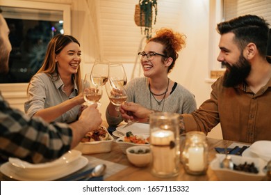 Group of cheerful friends toasting with wine while having dinner in dining room. - Shutterstock ID 1657115332