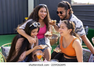 Group of cheerful indian friends having fun eating pizza talking laughing together, drinking cocktails at restaurant cafe. food and drinks. People enjoy holidays and vacations,  summer party fun,  - Powered by Shutterstock