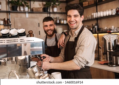 Group of cheerful men baristas wearing aprons working at the counter in cafe indoors, talking - Shutterstock ID 1460016914