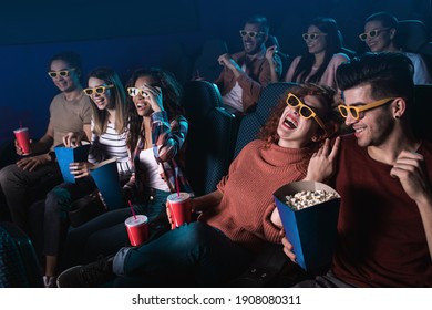 Group of cheerful people laughing while watching movie in cinema with 3D glasses.