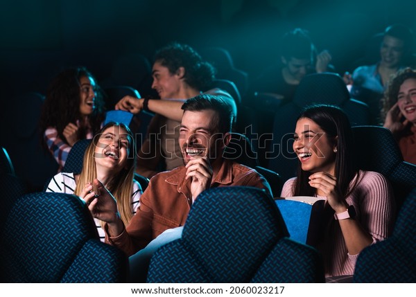 Group of cheerful people laughing while watching\
movie in cinema.