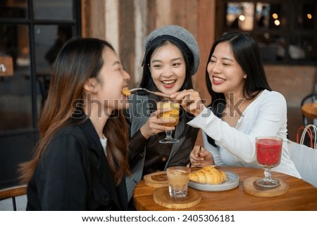 Group of cheerful and pretty Asian female friends are enjoying eating food and hanging out at a restaurant or cafe in the city. People and city life concepts