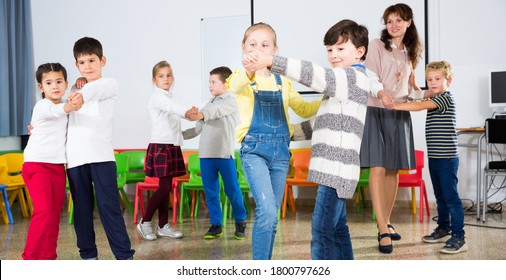 Group Of Cheerful School Kids Learning To Dance In Pairs With Their Teacher In Classroom On Recess