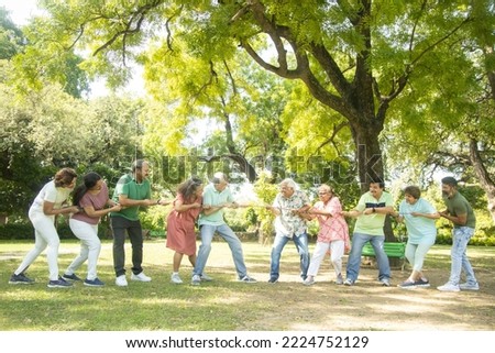 Group Of cheerful senior Indian People Play Tug of War Outdoor In summer Park. old men and women sport activity, Holidays and vacation, Enjoy Picnic, Health and fitness. Retirement, Stress free life. 