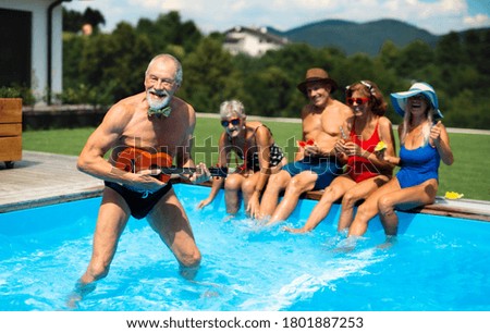 Group of cheerful seniors by swimming pool outdoors in backyard, party concept.