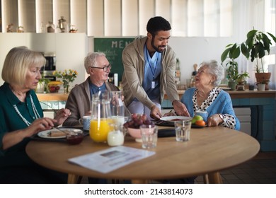 Group of cheerful seniors enjoying breakfast in nursing home care center. - Powered by Shutterstock