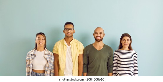 Group Of Cheerful, Smiling Mixed Race Multi Ethnic Youth. Diverse Team Of Young People With Happy Faces Standing In Row And Looking At Camera Against Blue Studio Background. Website Banner Or Header