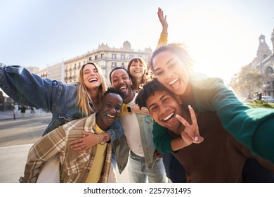 A group of cheerful students college friends having fun together as they travel through European cities. Happy community of diverse people. Selective focus on the smily couple taking the selfie. - Powered by Shutterstock