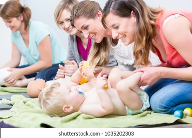 Group Of Cheerful Women Learning To Take Care Of Their Babies During Parenting Class For Young Mothers In A Contemporary Club For Moms