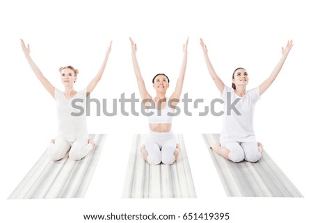 group of cheerful women practicing yoga on yoga mats isolated on white