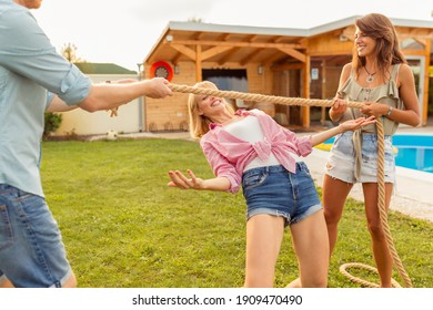 Group Of Cheerful Young Friends Having Fun At Summertime Outdoor Party By The Swimming Pool, Participating In Limbo Dance Contest, Passing Below The Rope While Dancing