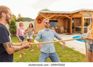 Group Of Cheerful Young Friends Having Fun At Summertime Outdoor Party By The Swimming Pool, Participating In Limbo Dance Contest, Passing Below The Rope While Dancing