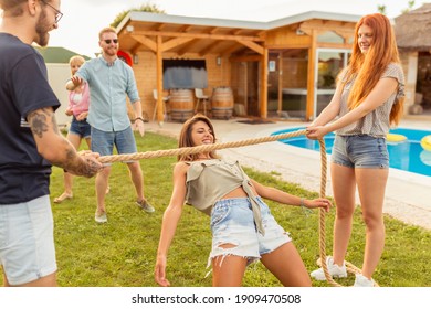 Group Of Cheerful Young Friends Having Fun At Summertime Outdoor Party By The Swimming Pool, Participating In Limbo Dance Contest, Passing Below The Rope While Dancing