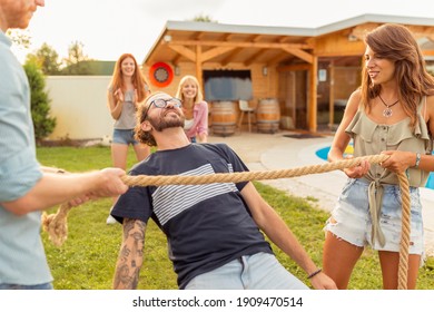 Group Of Cheerful Young Friends Having Fun At Summertime Outdoor Party By The Swimming Pool, Participating In Limbo Dance Contest, Passing Below The Rope While Dancing