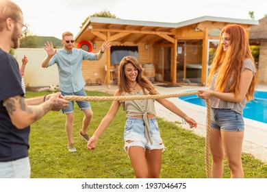 Group Of Cheerful Young Friends Having Fun At Summertime Outdoor Party By The Swimming Pool, Participating In Limbo Dance Contest, Passing Below The Rope While Dancing