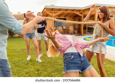 Group Of Cheerful Young Friends Having Fun At Summertime Outdoor Party By The Swimming Pool, Participating In Limbo Dance Contest, Passing Below The Rope While Dancing