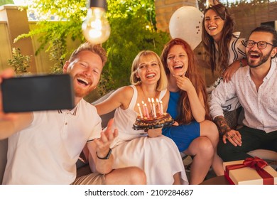 Group Of Cheerful Young Friends Having Fun Taking Selfies At Birthday Party, Hostess Holding Birthday Cake With Lit Candles