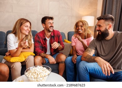 Group Of Cheerful Young Friends Having Fun Watching TV At Home, Eating Popcorn And Laughing 