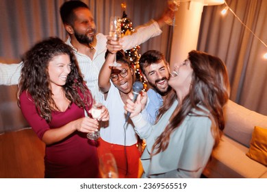 Group of cheerful young friends having fun at New Year's Eve party, singing karaoke, dancing and drinking champagne at midnight countdown - Powered by Shutterstock