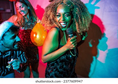 Group of cheerful young friends having fun singing karaoke and dancing at New Year's Eve party - Powered by Shutterstock