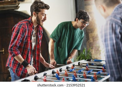 Group of cheerful young people friends playing table football carefree together - concept of happy fellows having fun with recreational activities - Powered by Shutterstock