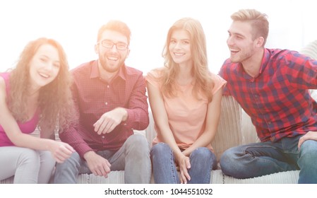 eine Gruppe fröhlicher junger Leute, die auf dem Sofa sitzen.