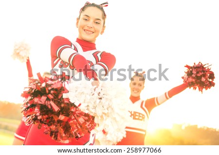 Group of cheerleaders performing outdoors  - Concept of cheerleading team sport training at high school during sunset - Tilted horizon composition and warm filter with sun backlighting