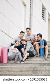 Group of cheerul young Asian people sitting on steps after training and taking selfie together