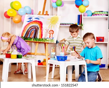 Group Child Painting At Easel In School.