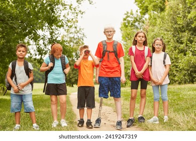 Group of children with backpacks walking on hiking trail in summer with boy with prosthestic leg - Powered by Shutterstock