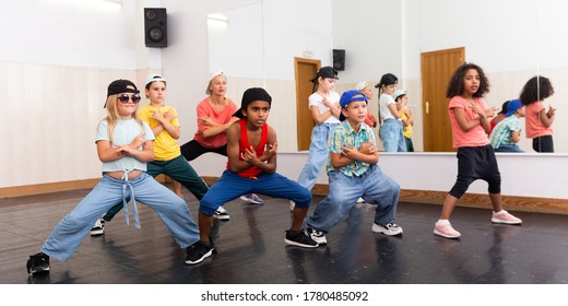 Group of children in casual clothes training hip-hop in class, learning modern dance movements
