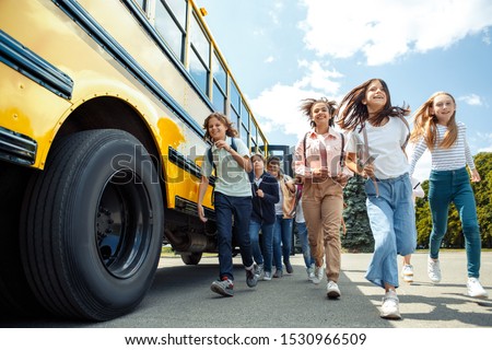 Group of children classmates running from school bus going back home looking forward smiling excited