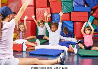 Group of children doing kids gymnastics in gym with nursery teacher