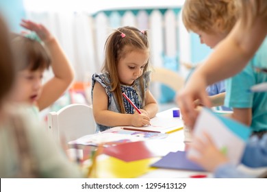Group of children drawing with nursery teacher in kindergarten - Shutterstock ID 1295413129