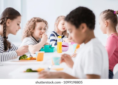 Group Of Children Eating Vegetables In The Dining Hall Of School