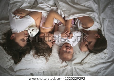 Similar – Image, Stock Photo Happy little girl holding doll and cookie while woman playing with a boy over the bed. Weekend family leisure time concept.