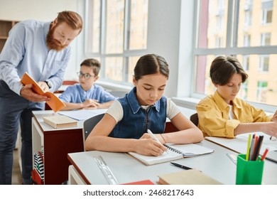 A group of children engage in learning activities, seated at bright desks in a lively classroom led by a male teacher. - Powered by Shutterstock