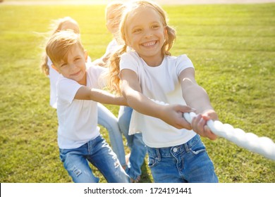 A group of children have fun playing in nature. Children jump over the rope. Warm summer evening with sunset light. - Powered by Shutterstock