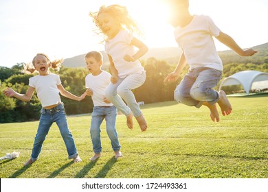 A group of children have fun playing in nature. Children jump over the rope. Warm summer evening with sunset light.