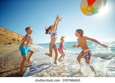 A group of children have fun playing at the sea. Children in bathing suits. Friends holding hands and running on the beach. High quality photo. - Powered by Shutterstock