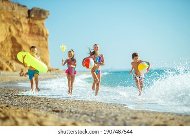 A group of children have fun playing at the sea. Children in bathing suits. Friends holding hands and running on the beach. High quality photo. - Powered by Shutterstock