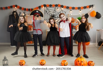 Group Of Children Having Fun And Doing Zombie Dance At Halloween Party At Home. Bunch Of Happy Kids Dressed Up In Different Spooky Costumes Walking And Dancing Like Zombies In Decorated Living Room