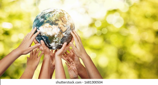 Group of children holding planet earth over defocused nature background with copy space