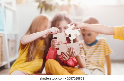 Group of children indoors playing together in jigsaw. Concept of solving of problem, togetherness, friendship and family relationship.