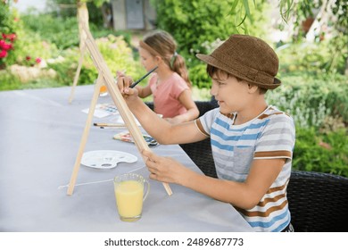 group of children paints watercolors sitting at a table in a summer garden. art therapy. KnowledgeForAll. Generation Z. Happy childhood. master classes in the fresh air